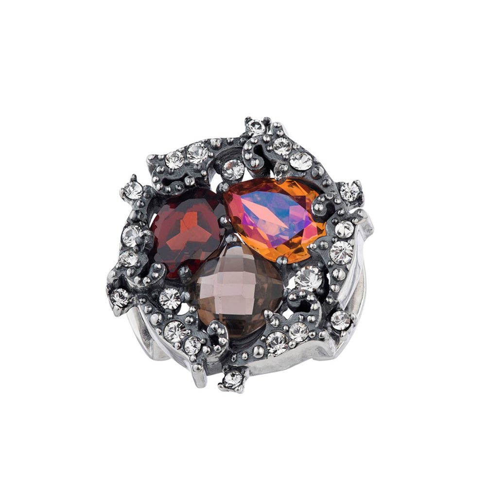 Photograph of an oxidized silver-toned cluster ring with an organic design featuring large dark red iridescent orange and smoky brown faceted gemstones accented by numerous small clear pavé crystals